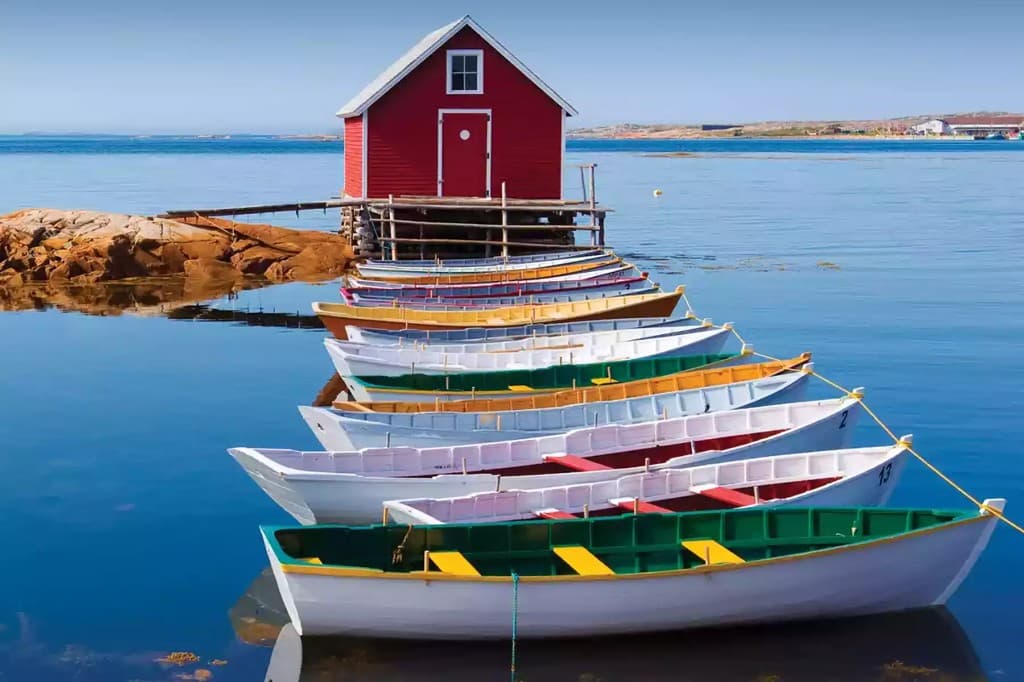 Colourful wooden dories moored in a row beside a red fishing stage on Newfoundland coastal waters